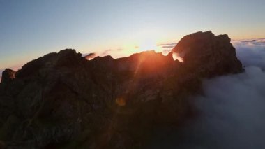 Portekiz 'in Madeira adasında gün batımında Pico do Arieiro' da bulutların üzerinde uçmak. Bulutların üstünde sihirli günbatımı manzarası dağ sıraları ve yürüyüşçülerin yanında uçuyor..