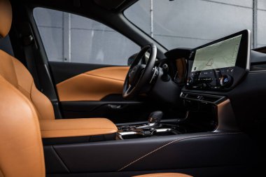 Yakından bakıldığında bronz deri koltuklar, kontrastlı dikişler, oyulmuş konsol ve Lexus RX 450h + iç mekanlı geniş bir merkezi dokunmatik ekran görünüyor..