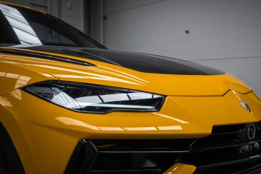 Üç çeyrek görünüm LED far, karbon fiber kaput ve kapalı boğa ibikli siyah fasya gösteriyor, yumuşak endüstriyel aydınlatma ve yansımalar hatları vurguluyor.