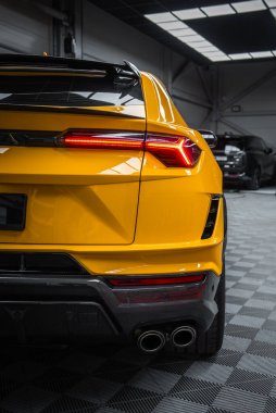 Arka üç çeyrek görünüm açısal LED arka lamba, çift egzoz, ve karbon fiber difüzör yumuşak üst ışık altında, bir showroom ayarı koyu bir sedan.