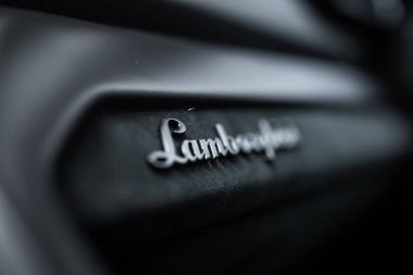 Sığ bir odak noktası Lamborghini senaryo rozetini Urus Performansı 'nın yumuşak karamsar ışıklandırması ve bulanık iç panelinde gösteriyor..