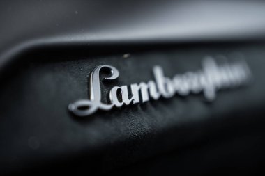 Macro çekimi krom Lamborghini senaryo rozeti üzerine yoğunlaşıyor. Büyük ihtimalle Urus Performante. Yumuşak karamsar ışıklandırma ve bulanıklık metalik kaplamayı vurguluyor.