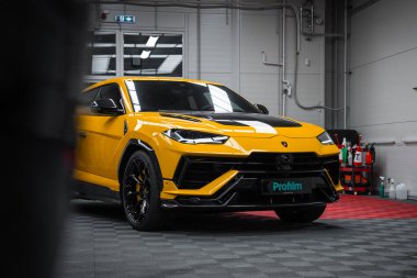Sarı bir Lamborghini Urus Performante kapalı bir stüdyoda oturuyor, profilm plakası görünür, aero girişleri ve yumuşak ışıkların altında parlak siyah tekerlekleri var..