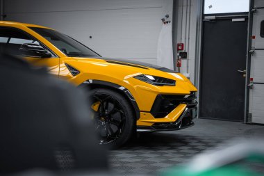 Parlak sarı bir Lamborghini Urus Performante LED farlar, karbon kaput, siyah aero aksanları, büyük siyah tekerlekler ve sarı kalibreli.