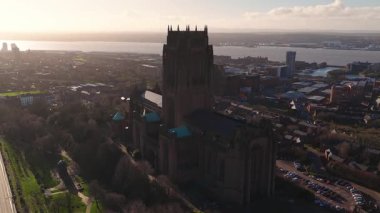 İngiltere, Liverpool 'da hava gündoğumu üstgeçidi. Kamera yörüngeleri katedral kulesi, turkuaz çatı aksanlarını, uzun gölgeleri, park edilmiş arabaları, ufuk çizgisini ve Mersey Nehri 'ni gösteriyor..