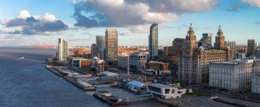 Liverpool 'un hava gündoğumu görüntüsü, Mersey Nehri solda, ufuk çizgisi sağda. Kraliyet Karaciğer Binası, Cunard Binası, Liverpool Müzesi, Albert Limanı, Turnalar, rüzgar türbinleri.