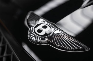 Bentley Bentayga Speed 'in cilalı kanatlı kaput rozeti içeride parlar, krom ayrıntılar usulca yansıtır, ön ızgara ipuçları lüks bir SUV ve titiz bir bitiriş izlenimi verir..