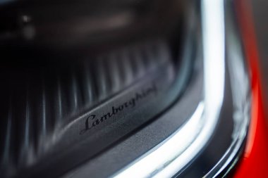 Sıkı makro, Lamborghini senaryosunu ve bir atölyede gündüz çalışan LED gündüz kuşağını gösteriyor. Parlak siyah bezel ve sığ alan derinliği hassasiyet ve markalaşmayı vurguluyor.