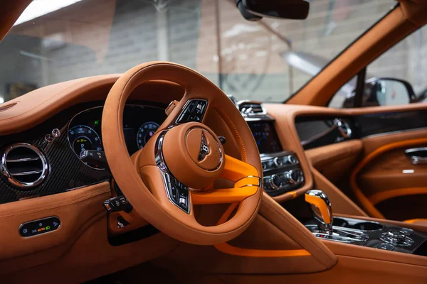 Kapalı sürücü koltuğu görüntüsü turuncu deri, karbon fiber çizgi, düğmeli şalter, kanatlı B tekerlek, dijital küme, çift ekran, mücevherli havalandırma, sıcak ışıklandırma gösteriyor..