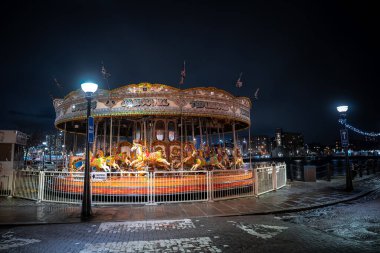 Eski bir atlıkarınca geceleri Liverpool Royal Albert Rıhtımı 'nın rıhtımında döner. Sendika bayrakları dalgalanıyor, ıslak kaldırım taşları parlıyor ve şenlikli ip ışıkları parlıyor..