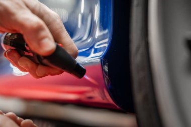 Bir teknisyen, bir krupiye atölyesinde tekerlek kemerinin yakınına kalem sürer. Yumuşak yönlü ışık ve yansımalar hatları, hassasiyeti ve sığ derinliği gösterir..