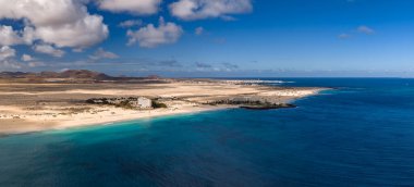 Hava görüntüsü Fuerteventura, Kanarya Adaları 'ndaki Atlantik sularına doğru kıvrılan altın kumları gösteriyor. Kayalık kayalıklar, tatil beldeleri, kum tepeleri ve bulutlu öğle ışığı..