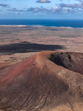 El Cotillo yakınlarındaki Fuerteventura 'da paslı bir koni ve kraterin hava görüntüsü. Lav tarlaları, seyrek yollar ve yumuşak öğleden sonra ışığında Atlantik ufku..