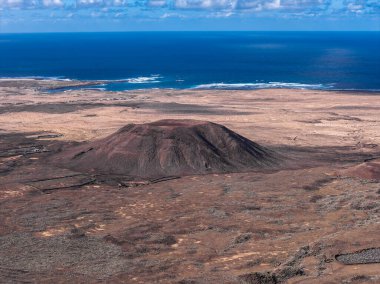 Fuerteventura, Kanarya Adaları 'ndaki soyu tükenmiş bir külah. Düzleştirilmiş zirve, radyal lav akıntıları, soluk kum düzlükleri, seyrek yerleşimler, Atlantik ufku..