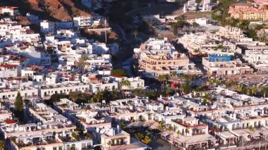 Kanal, marina, mavi köprüler, palmiye güvertesi, plaj salonları, tekneler, teraslar sıcak öğleden sonra aydınlığında Puerto de Mogan, Gran Canaria 'nın havadan 4K görüntüsü..