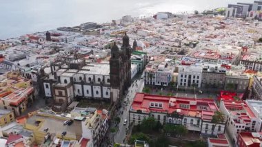 Las Palmas de Gran Canaria 'daki Vegueta üzerinde gün ışığı süzülüşü Santa Ana Katedrali, plazalar, palmiye caddeleri, insanlar, kırmızı bir festival gösterisi ve Atlantik ufkunu gösteriyor..