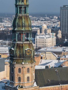 Hava gözlem merkezleri Letonya, Riga 'daki St. Peter Kilisesi kulesi ve saati gösteriyor. Eski şehrin çatıları karla kaplı. İsa 'nın Doğuşu Katedrali ve gökdelenler gün ışığında görünür..