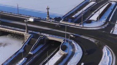 Yüksek bir hava çekimi Riga, Letonya 'da bir taş köprü ve yol kavşağını gösteriyor. Süslü lamba sütunları, merdivenleri ve kıvrımlı bir alt geçidi olan donmuş bir nehir kıyısında..