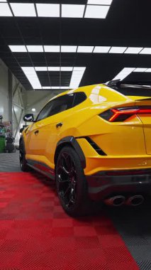 Arka üç çeyrek görüntü altıgen siyah tekerlekler, dört egzozlar, Y arka lambaları, yan kapaklar gösteriyor. Parlak panelli ayrıntılı bir atölyedeki sürücü kapısına kamera yansıtıyor.