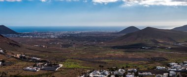 Atlantik 'e, La Geria lav tarlalarına ve üzüm bağlarına, sahildeki Arrecife' e, koni şeklindeki tepelere, fincanlara ve palmiye kaplı köylere bakan Lanzarote volkanik iç mekanının havadan görüntüsü..