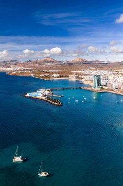 Arrecife, Lanzarote 'nin hava görüntüsü Islote de Fermina' yı gösteriyor, bir köprü, Gran Hotel Arrecife, Playa del Reducto, yelkenliler, volkanik koniler ve gün ortası ışığı..