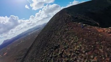 Hava aracı Fuerteventura 'da volkanik bir çıkıntının izini sürüyor, kül konileri, rüzgar türbinleri, taş duvarlar, lav düzlükleri, kıyı şeridi ve görülebilir küçük bir kasaba..