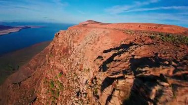 İnsansız hava aracı, Lanzarote 'nin Mirador del Rio yakınlarındaki Famara kayalıklarını takip ederek volkanik kolonları, dar yolları, küçük figürleri, güneş ışığını ve Atlantik kıyısını altın saatinde ortaya çıkarıyor..