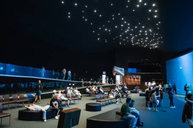 Las Palmas 'taki sönük ışıklı Poema del Mar Akvaryumu, Gran Kanaryası ziyaretçiler oturup izlerken kıvrımlı bir pencere, yıldız ışıkları ve bir köpekbalığı başı girişi gösteriyor..