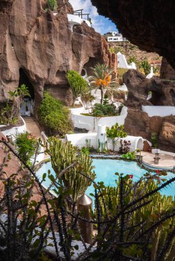 Organik beyazlatılmış teraslar, turkuaz bir havuz ve kaktüs Lanzarote 'deki Lagomar Müzesi' ndeki volkanik kayalarda bulunuyor. Gün ortası ışığı avuçlara ve suya gölge düşürür.