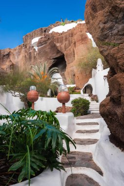 Duvarları beyazlatılmış taş basamaklar Lanzarote 'deki Lagomar Müzesi' ndeki volkanik kayalıklara çıkıyor. Terracotta lambaları ve sulu yollar canlı bir gökyüzünün altında..