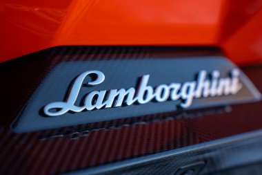 Macro view Lamborghini senaryosunu karbon panelde gösteriyor, üstünde turuncu kaporta, yüzeysel alan derinliği, tırmık ışığı, sergi odası ya da stüdyo ayarı.