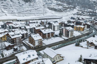 Zermatt, İsviçre 'nin havadan görünüşü, pansiyonlarda ve dairelerde kar, kıvrımlı bir nehir, teraslı kayalık yamaçlar, ve yumuşak bulutlu ışık altında düzenli sokaklar..