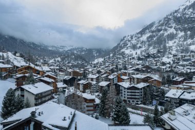 İsviçre 'nin Zermatt kentindeki kar manzarası, dağ evleri, oteller ve Zermatt kilise kulesiyle kaplıydı. Bulutlar Matterhorn' u bulutlu bir kayak sezonunda saklıyordu..