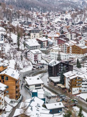 Zermatt, İsviçre 'nin havadan görünüşü, Chalets, oteller, Zermatt kilise alanı ve Gornergrat demiryolu ile. Kar bulutlu bir vadide, yumuşak bulutlu bir ışık altında çatıların tozunu alır..