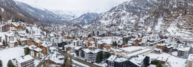Zermatt, İsviçre 'nin havadan görünüşü, dağ kulübeleri, oteller ve sarp bir vadide Zermatt kilisesi kulesi, yumuşak bulutlu bir ışık, bulutlu zirveler, Matterhorn gizli.