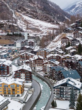 Zermatt, İsviçre 'nin havadan görünüşü, kar tozlu Chalet' ler, lüks oteller, ve serin, serin gün ışığı altında vadide kıvrılarak ilerleyen turkuaz Vispa Nehri..