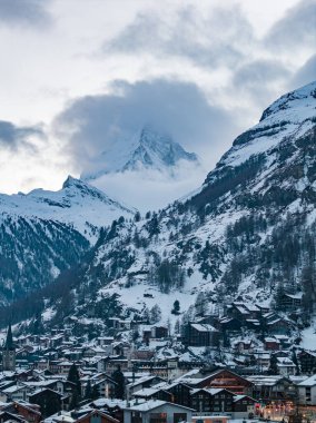 İsviçre 'nin Zermatt kentindeki kar tozu kilisenin tebeşirler arasında yükselmesine yol açıyor. Matterhorn ağır bulutları deliyor. Öğleden sonra ışığı mavi gri tonlar ve sıcak pencereler yapar..
