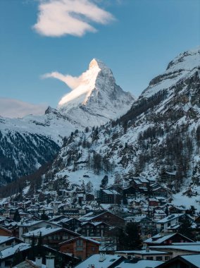 Zermatt, İsviçre gündoğumunda Matterhorn 'un altında yer alır. Chalet çatıları, lüks oteller, ve kilise vadi boyunca kar ve taze sabah ışığı ile kaplı..
