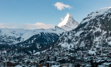 Kar örtülü Zermatt, İsviçre Matterhorn, dağ evi tarzı evler, lüks oteller ve öğleden sonra geç saatlerde Zermatt Kilisesi 'ni gösteriyor..