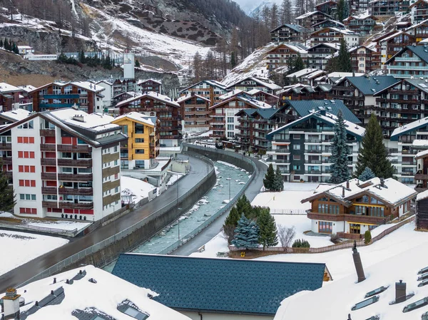 Hava görüntüsü İsviçre, Zermatt 'ı Matter Vispa' nın yanındaki dağ evi otellerini gösteriyor. Kar çatıları, yemyeşil, teraslı yamaçlar ve alp yamaçları bulutlu ışık altında görünür..