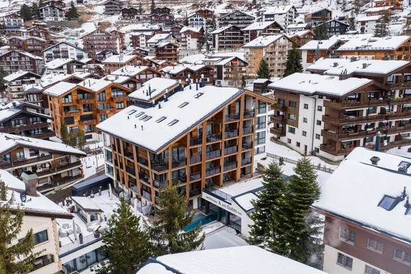 İsviçre 'nin Zermatt kentinin havadan görünüşü. Alp çadırlarının ortasında modern bir dağ evi oteli. Kar battaniyeleri çatılar ve şeritler, kozalaklı sokaklar ve bulutlu ışık kompakt kasabayı yumuşatıyor..