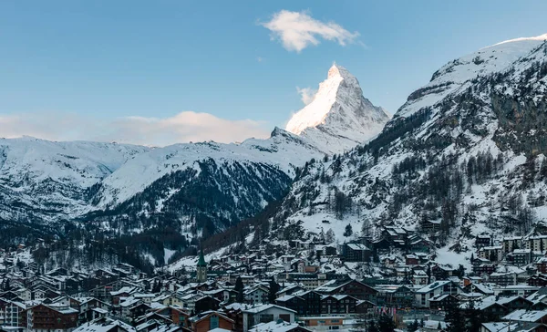 Kar örtülü Zermatt, İsviçre Matterhorn, dağ evi tarzı evler, lüks oteller ve öğleden sonra geç saatlerde Zermatt Kilisesi 'ni gösteriyor..