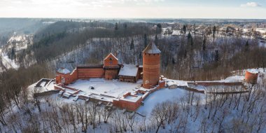 Sigulda, Letonya 'daki Turaida Kalesi' nin havadan görünüşü, kırmızı tuğlalı kulesi, perde duvarları, Gauja Nehri vadisinde karlı avlusu, yapraksız ormanlar ve gündüz tepeleri var..