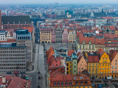 Wroclaw, Polonya 'nın hava sahnesinde Rynek pastel konutlar, dekoratif gablonlar ve Aziz Mary Magdalene Kilisesi çatısı solda bulutlu bulutlu bir sis ile görülüyor..