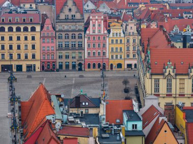 Polonya 'daki Wroclaw Pazar Meydanı' nın hava manzarası, yumuşak bulutlu kış ışığı altında geniş bir kaldırım taşı plazasına bakan süslü cepheli pastel gablı kasabaları gösteriyor..