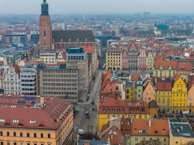 Wroclaw, Polonya 'nın hava manzarası Pazar Meydanı, St. Elizabeth Kilisesi, pastel cepheler, dik kırmızı çatılar, dar sokaklar ve ufukta bulutlu şehir şebekesi gösteriyor..
