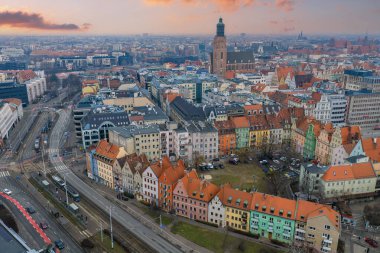 Wroclaw, Polonya 'nın hava manzarası St. Elizabeths kilise kulesini, gengelli konutları, tramvay kuyruklu caddeleri ve kış günbatımında modern binaları gösteriyor..