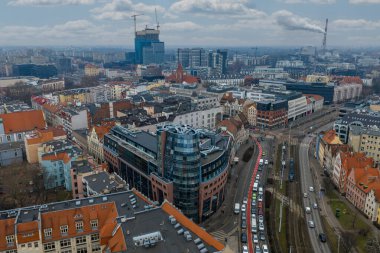 Merkezi Wroclaw, Polonya 'nın havadan görünüşü, turuncu çatıları, cam ofisleri, tramvay rayları ve arabaları var. Yuvarlak köşe ofisi Yeni Avrupa Merkezi 'ndeki vinçlere ve yüksek binalara zıt düşüyor.