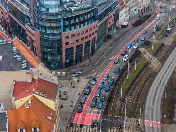 Hava görüntüsü Wroclaw 'da bulutlu bir günde kavis bulvarı, kırmızı otobüs veya bisiklet yolu, çimenli medyan üzerindeki tramvay rayları, cam şehir simgesi ve konaklar, arabalar ve yayaları gösteriyor..