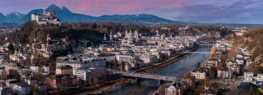 Solda Hohensalzburg, Salzburg, Salzburg Katedrali, köprüleri olan Salzach Nehri ve sonbaharın sonlarında hafif gün ışığında Alpler 'in tozunu alan kar manzarası.